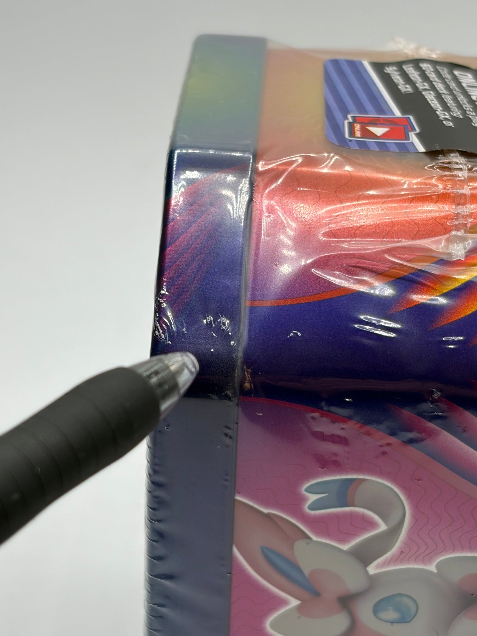 Lowkey Stock factory sealed 2018 Pokemon Leafeon GX tin corner detail with plastic wrap and pen pointing to edge