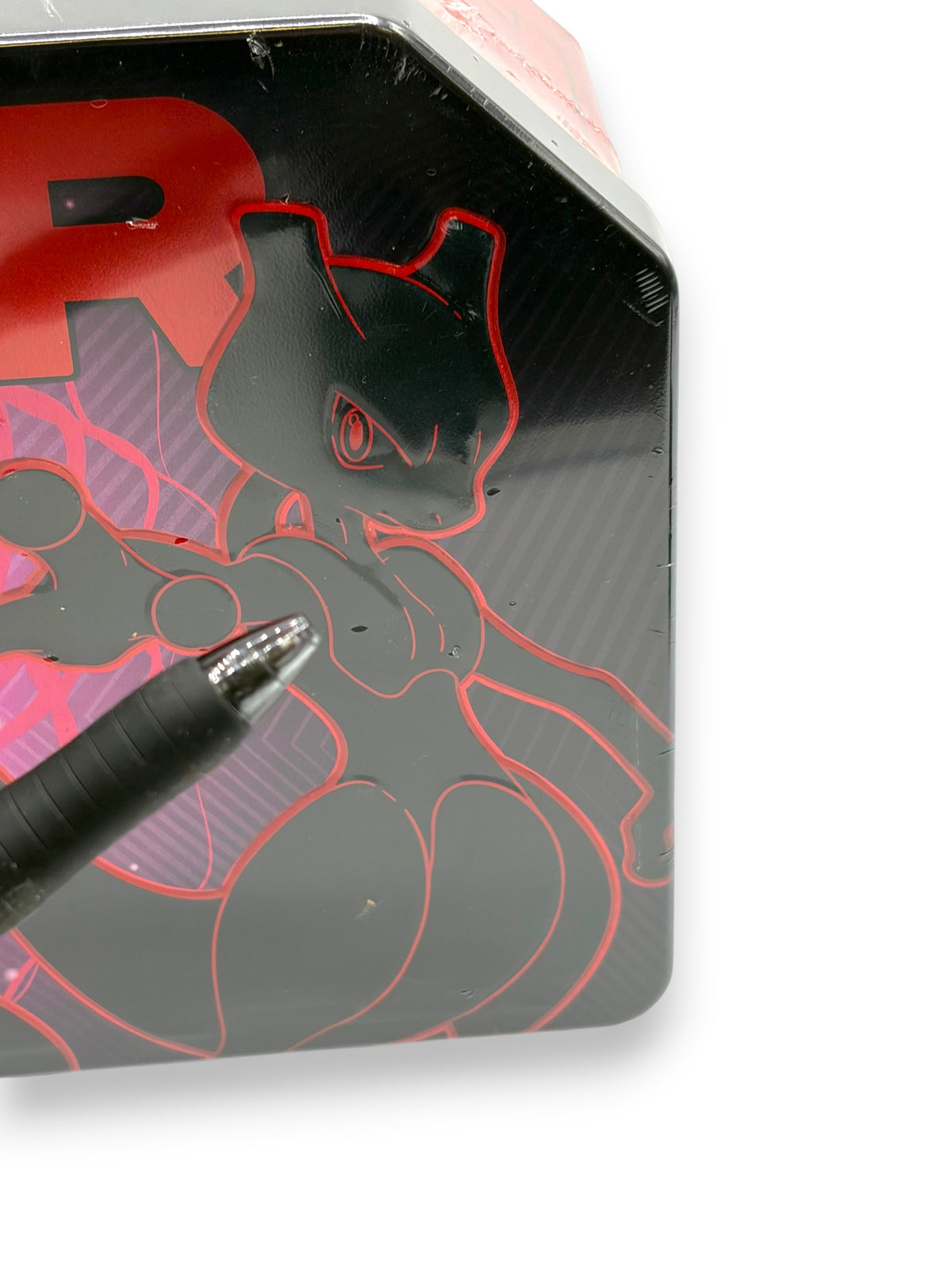 Lowkey Stock Pokemon TCG Team Rockets Mewtwo EX tin featuring black and red artwork with a pen pointing to seal wear