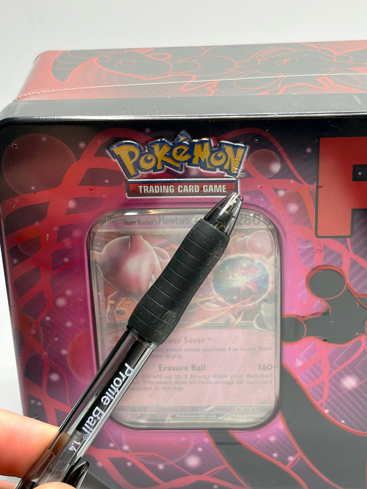 Lowkey Stock Pokemon TCG Team Rocket Mewtwo EX tin featuring a black pen pointing to the sealed packaging surface