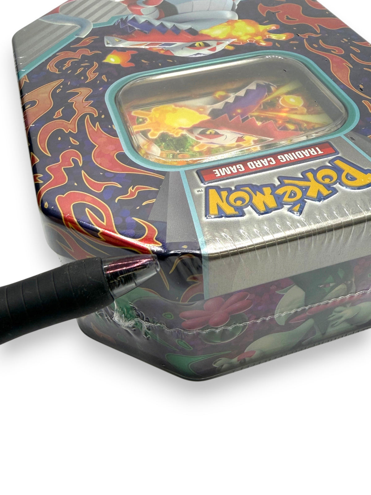 Lowkey Stock sealed Pokemon TCG Paldea Partners tin featuring Skeledirge ex with a pen pointing to a plastic tear